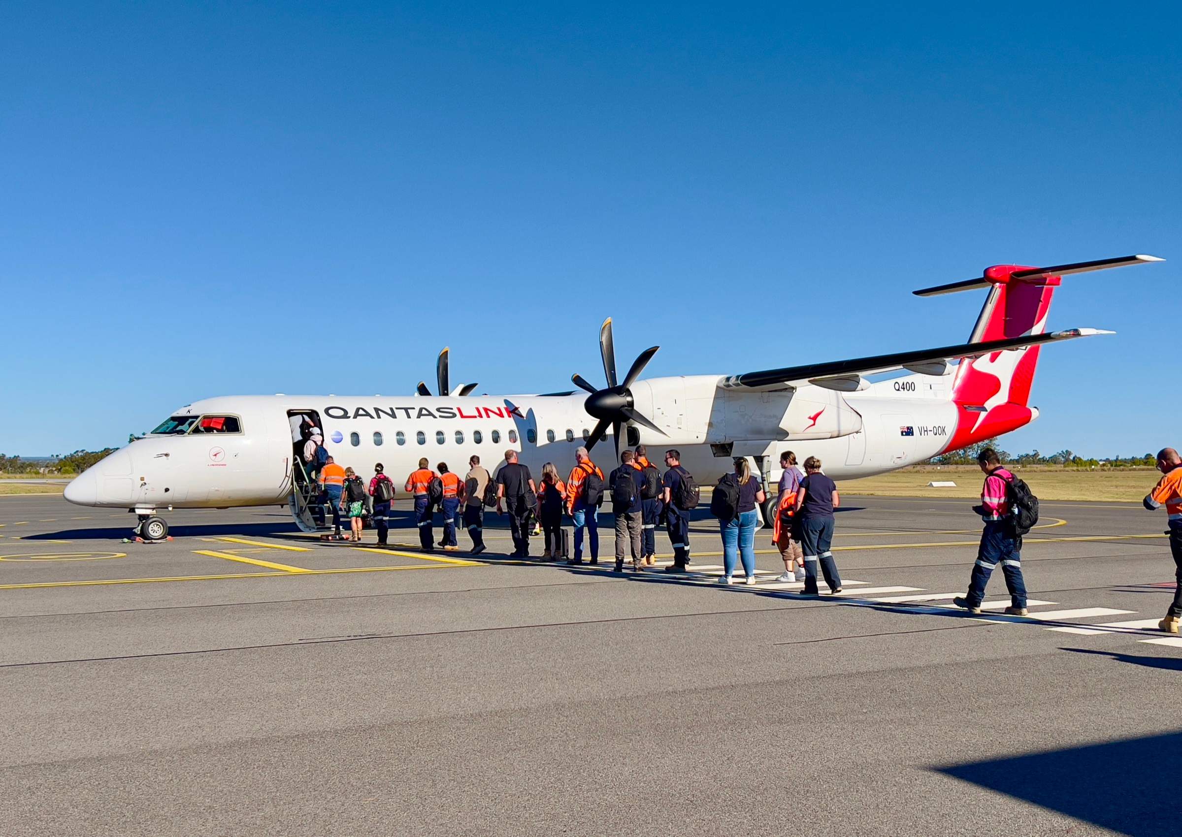 FIFO workers in hi-vis uniforms boarding a small plane at a regional airport